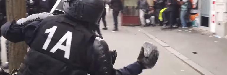 Un policier lance un pavé sur les manifestants du 1er mai